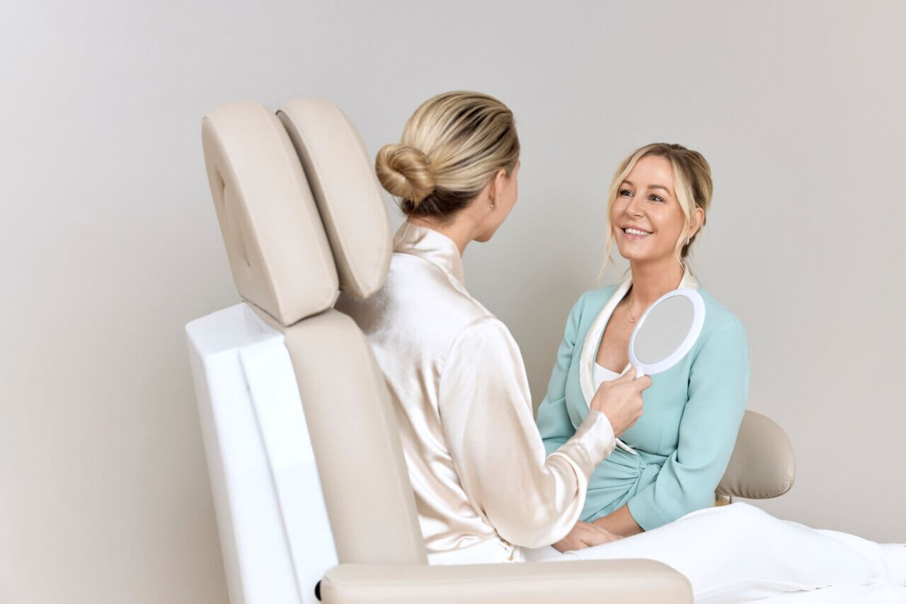 klient der holder et spejl og smiler til behandler