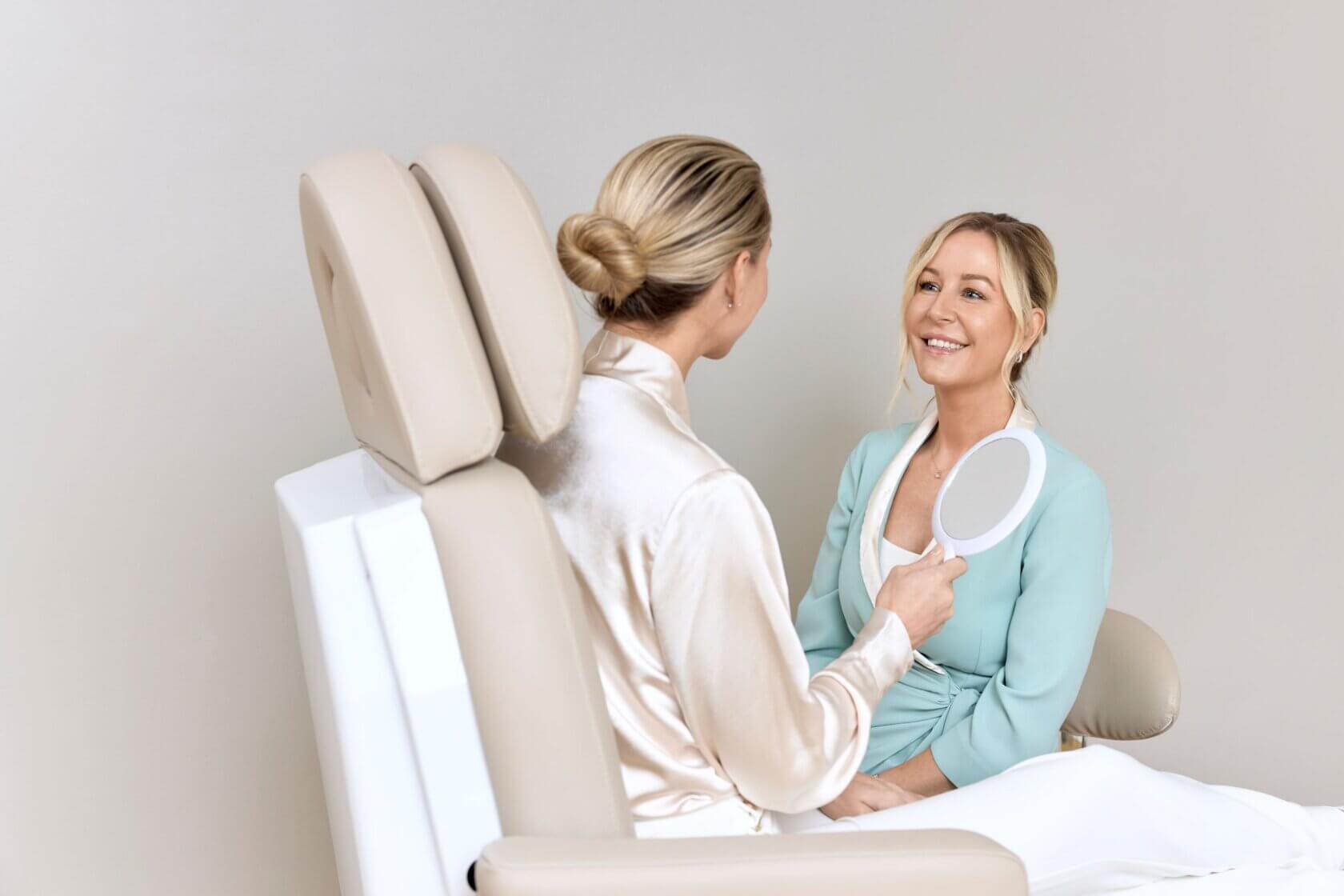 klient der holder et spejl og smiler til behandler